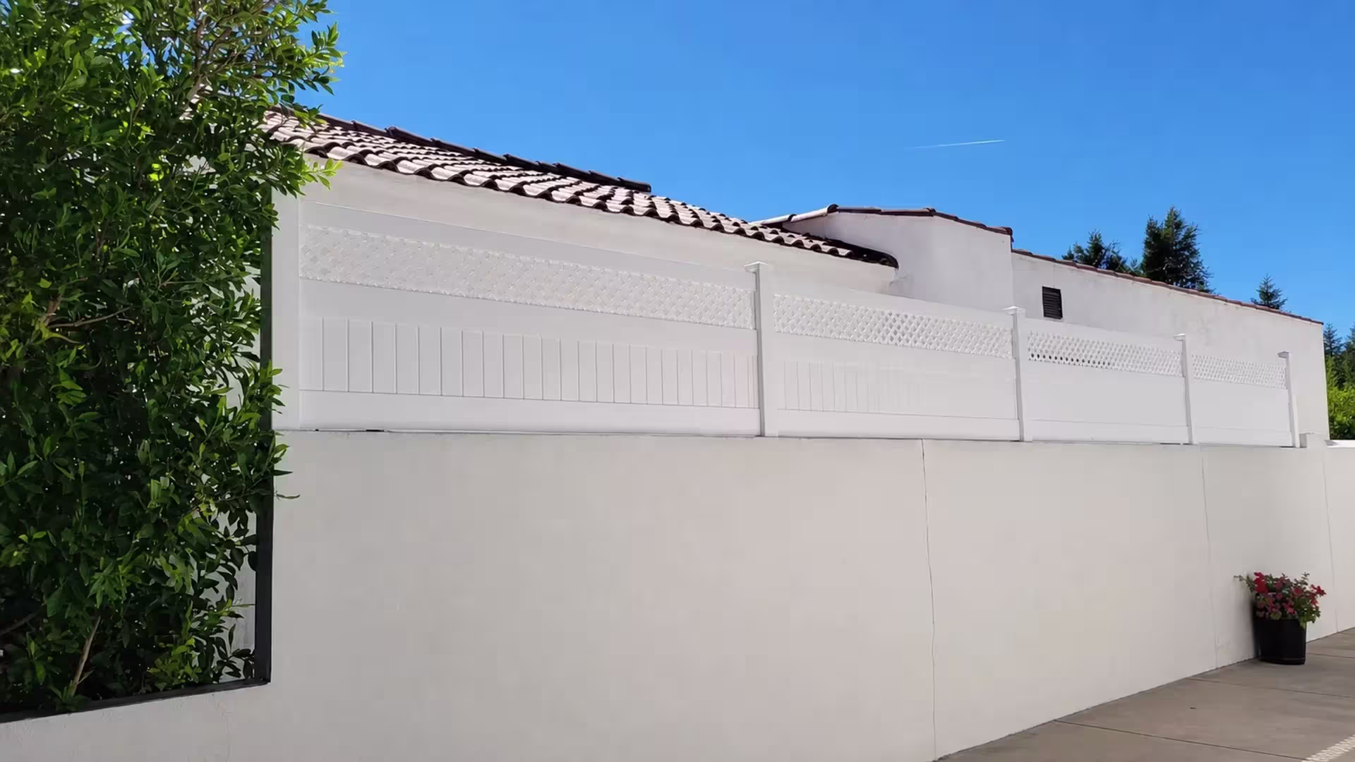 A crisscross lattice band tops a White custom vinyl wall topper on a stucco wall below a tiled roofline