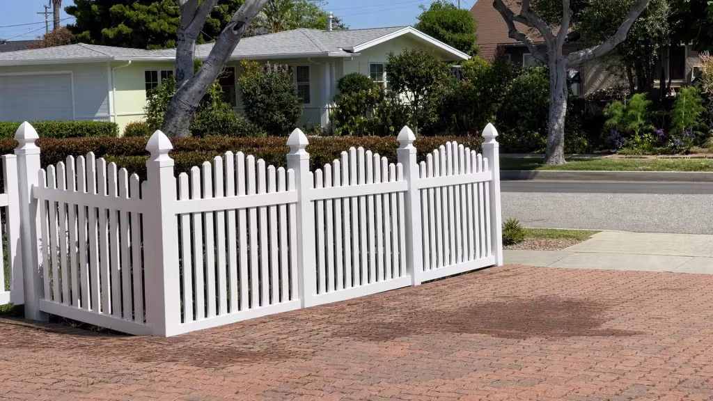 Utility wires cross overhead as a White vinyl dog-ear fence recedes past the garage