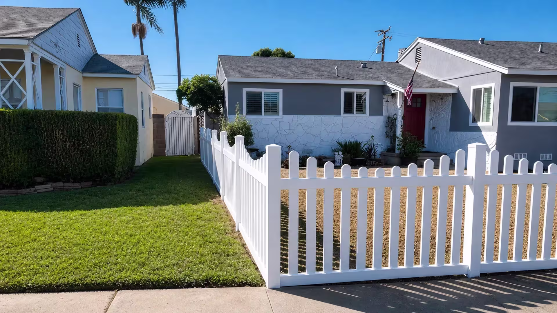 The White vinyl dog-ear fence rounds an L-shaped corner past palms toward the side yard