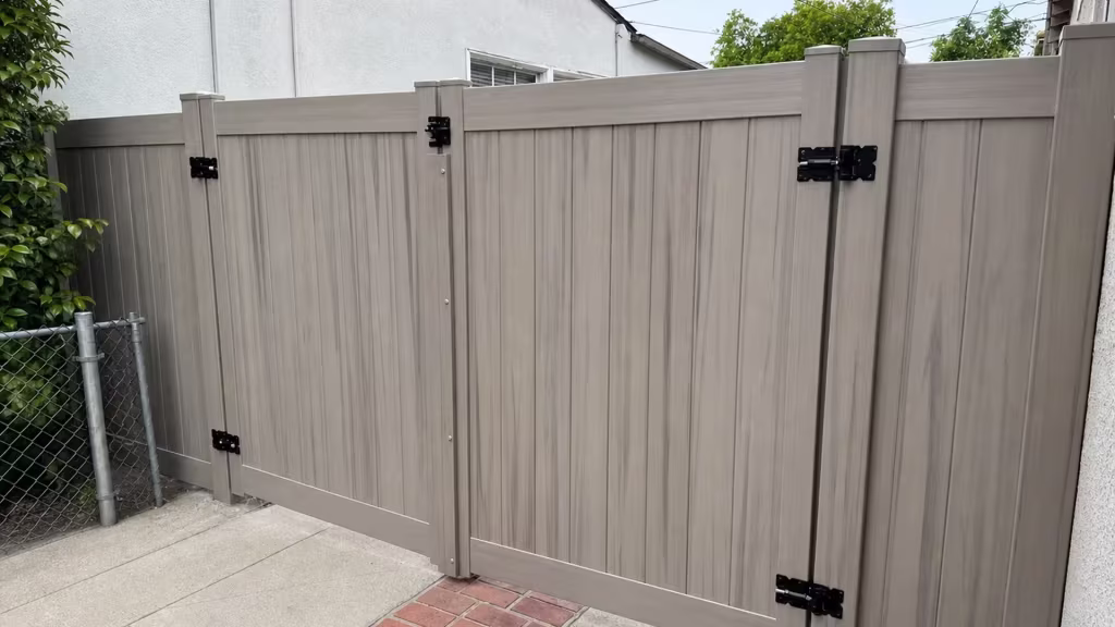 Mesquite vinyl driveway gate with matching square posts standing along a red brick paving strip