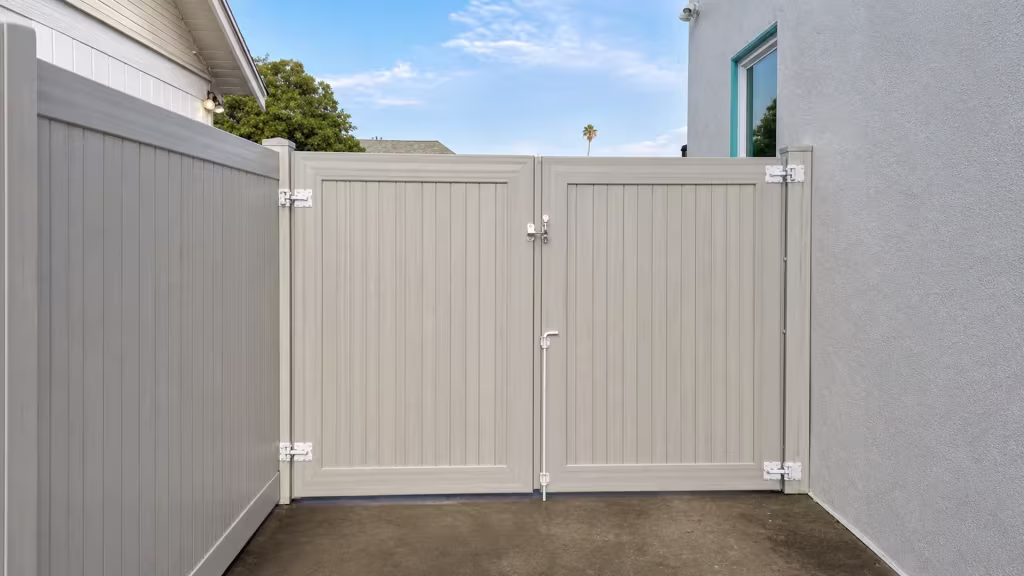 Mesquite vinyl driveway gate closing a narrow side passage between a fence return and a stucco house wall