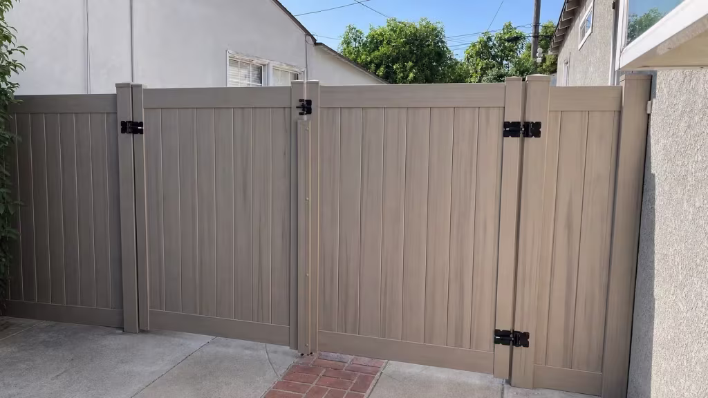 Mesquite vinyl driveway gate with two full-height openings set between two neighboring stucco buildings