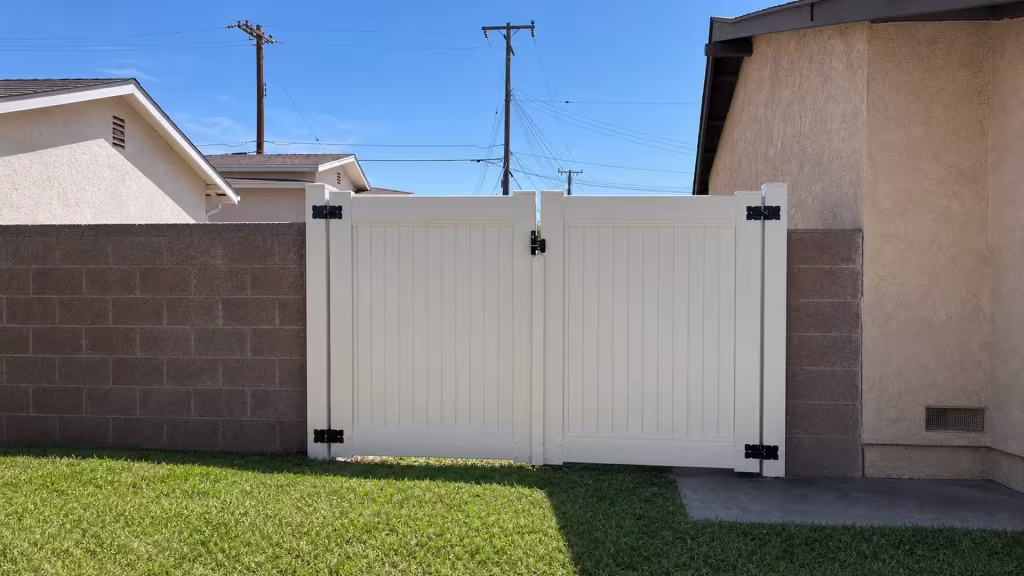 Tan vinyl driveway gate with two equal swinging leaves closing the gap between two masonry walls