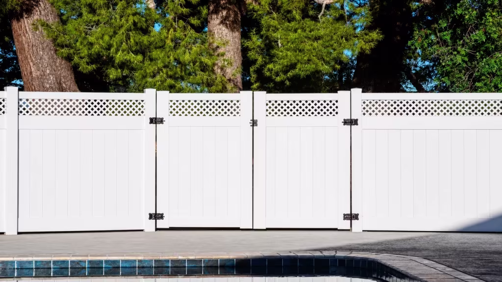 Poolside White vinyl driveway gate sits within a privacy fence run beside the paved deck