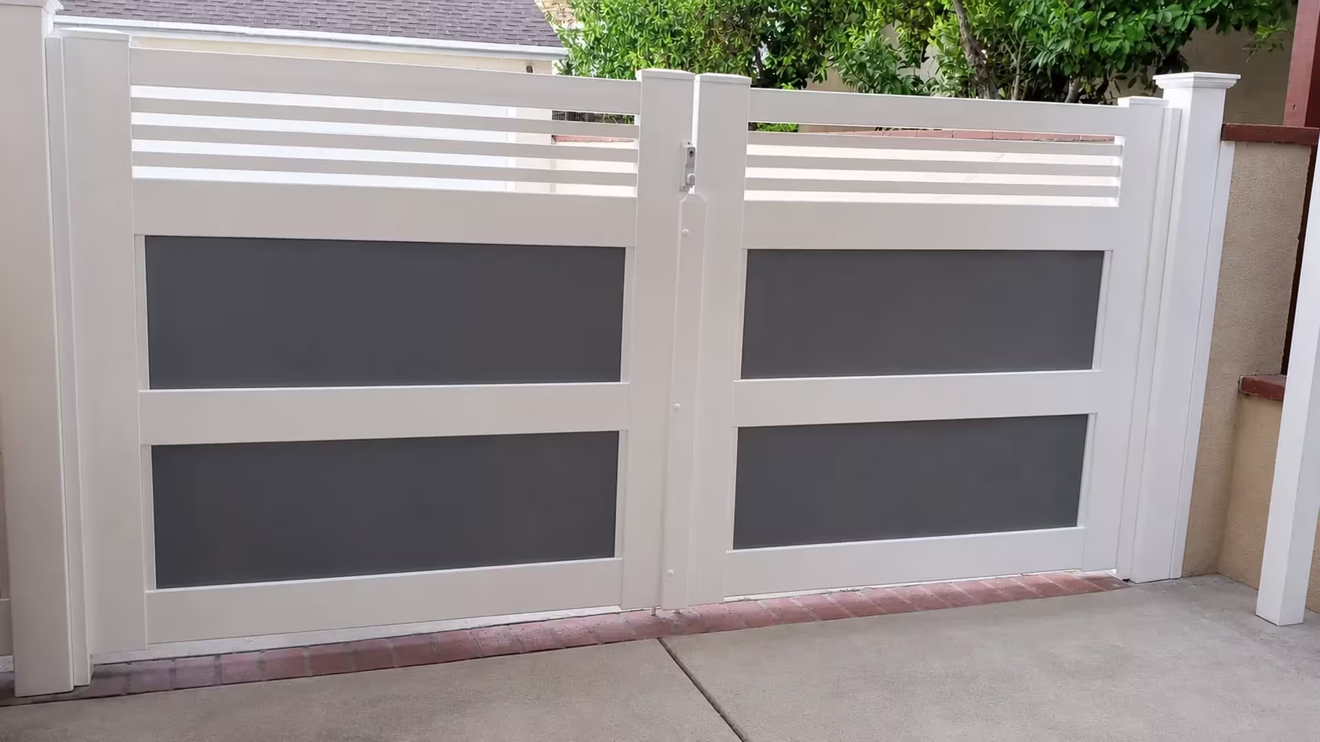 Acrylic-panel White vinyl double driveway gate stands beside a masonry boundary wall and brick strip