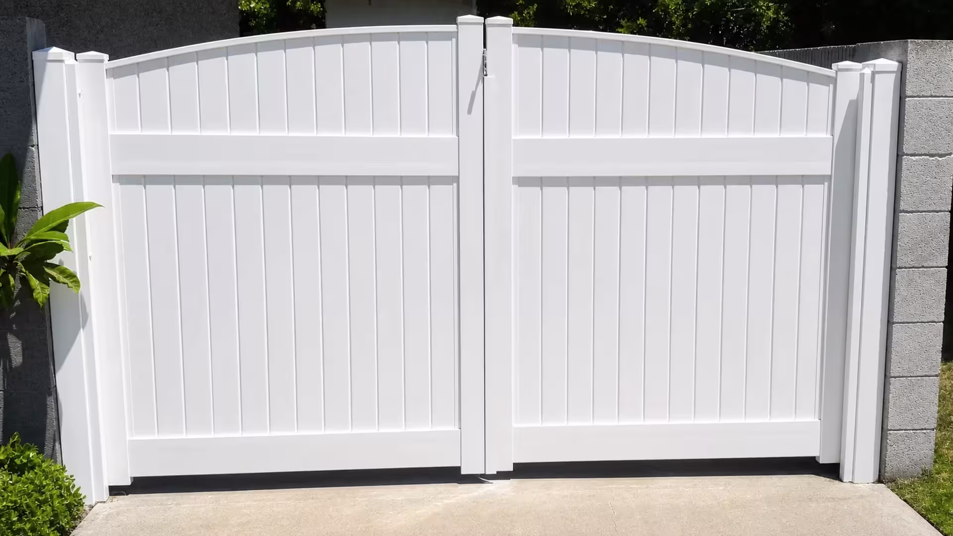 Gray concrete block walls border this arched-top White vinyl privacy driveway gate