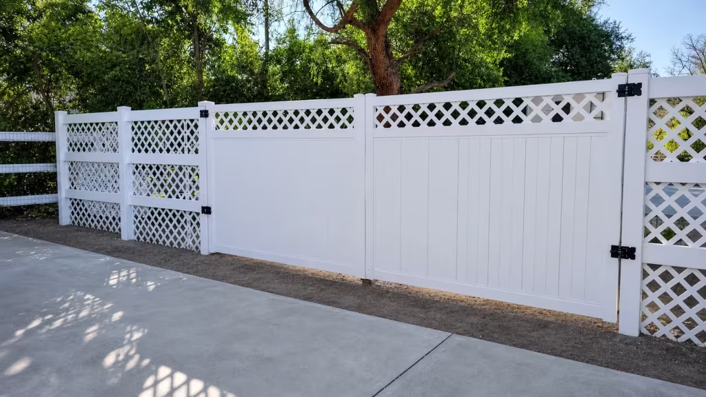White vinyl driveway gate with a diamond lattice band above solid privacy boards on each leaf
