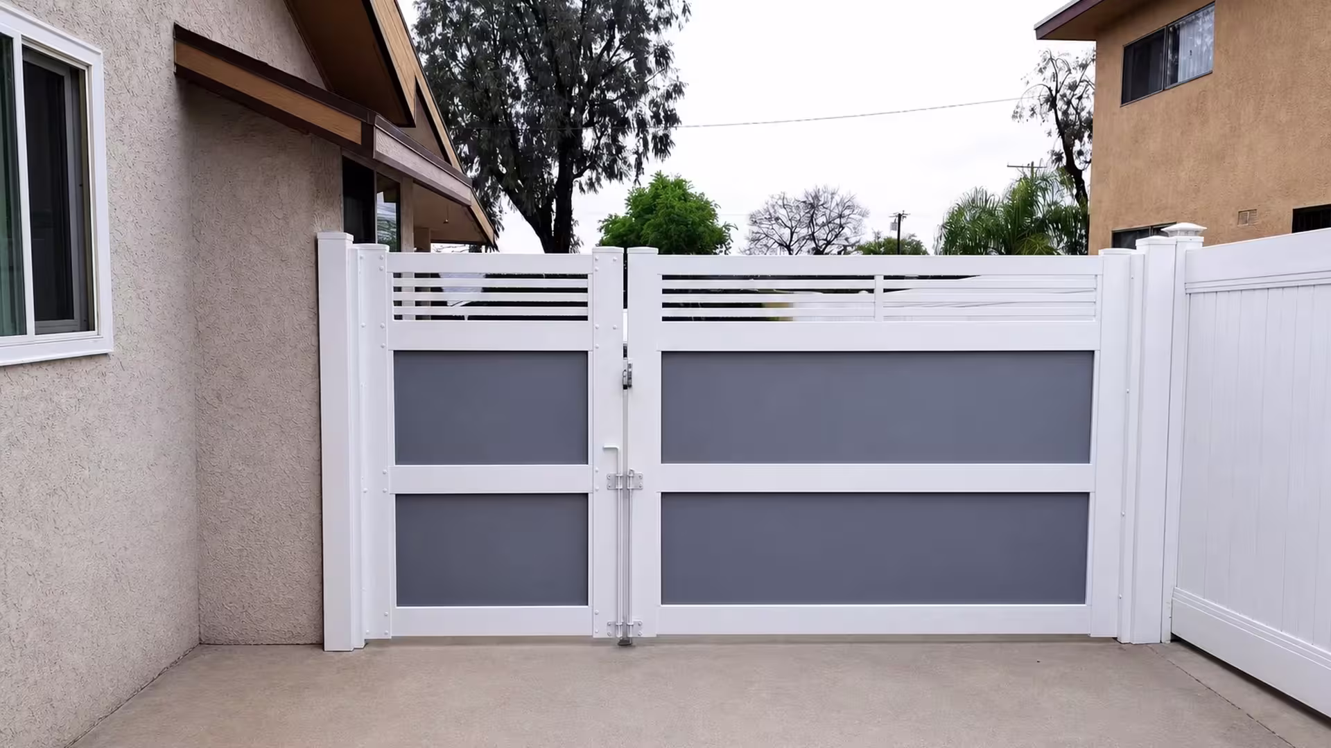 Stacked gray acrylic inset panels sit beneath the horizontal slats of this White vinyl driveway gate