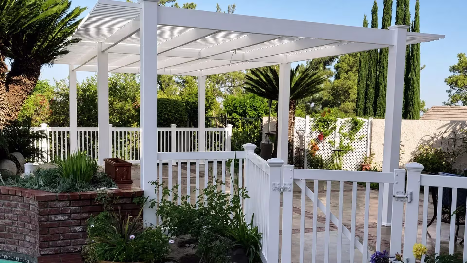Open lattice White vinyl freestanding patio cover set beside brick planters at the pool edge