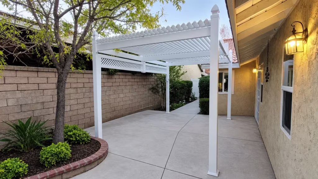 Pyramid capped front posts mark this White vinyl freestanding patio cover beside a brick planting bed