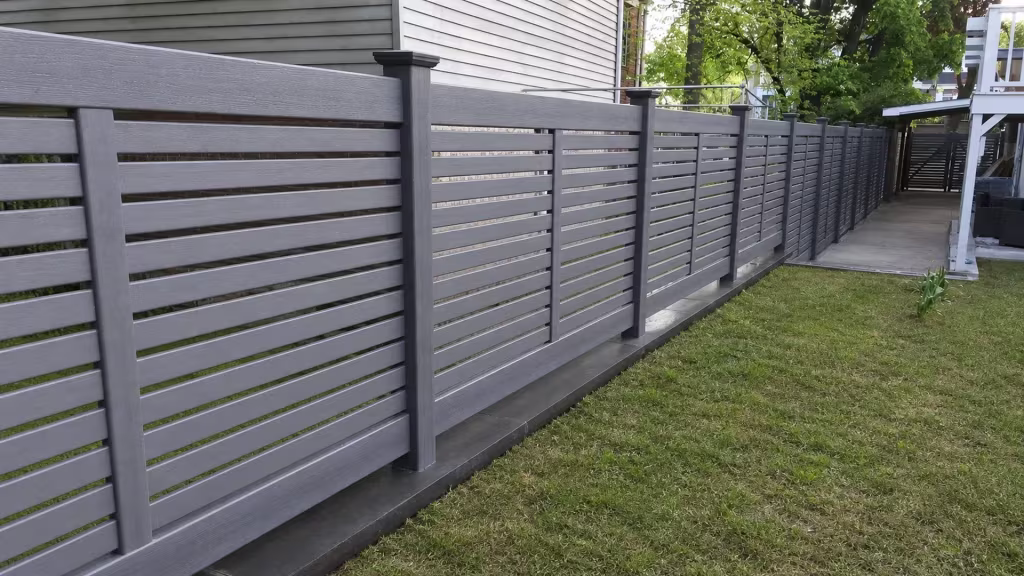 Arctic Blend vinyl picket fence running beside a gray-sided house toward the rear patio deck