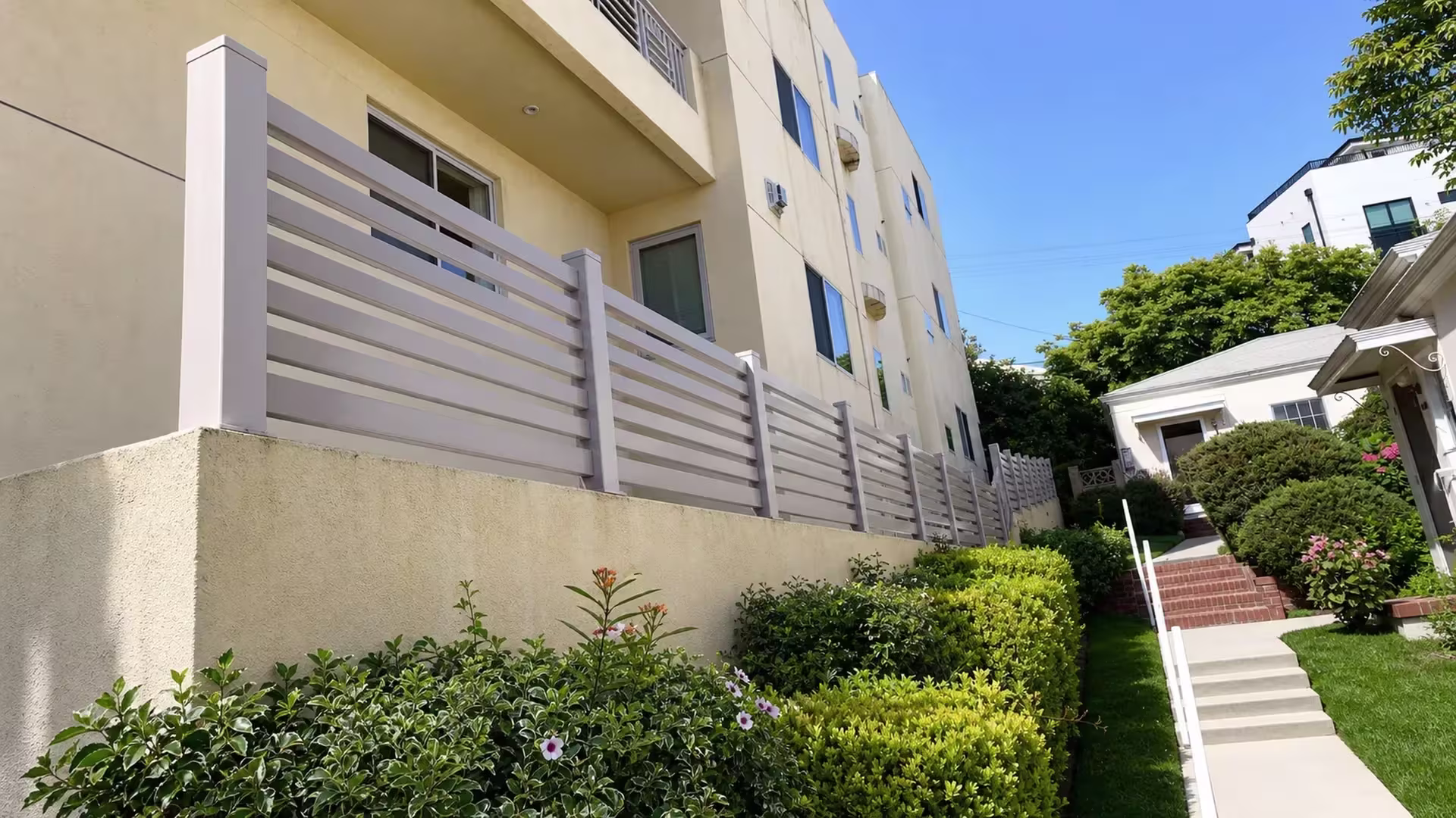 Clay vinyl picket fence mounted continuously atop a beige stucco wall on a balcony