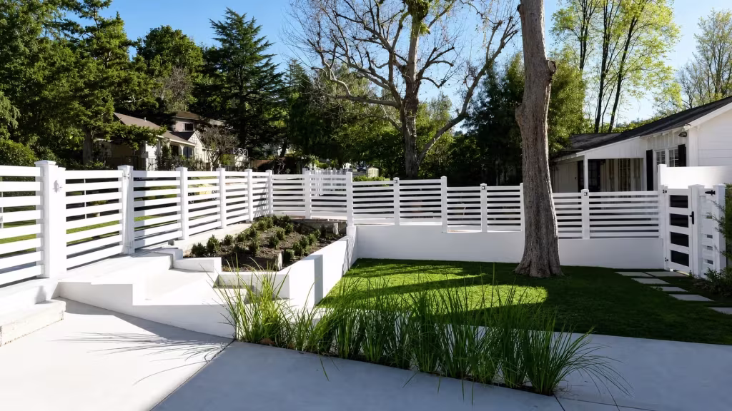 Stepped White vinyl picket fence tops masonry planter walls that turn through the yard
