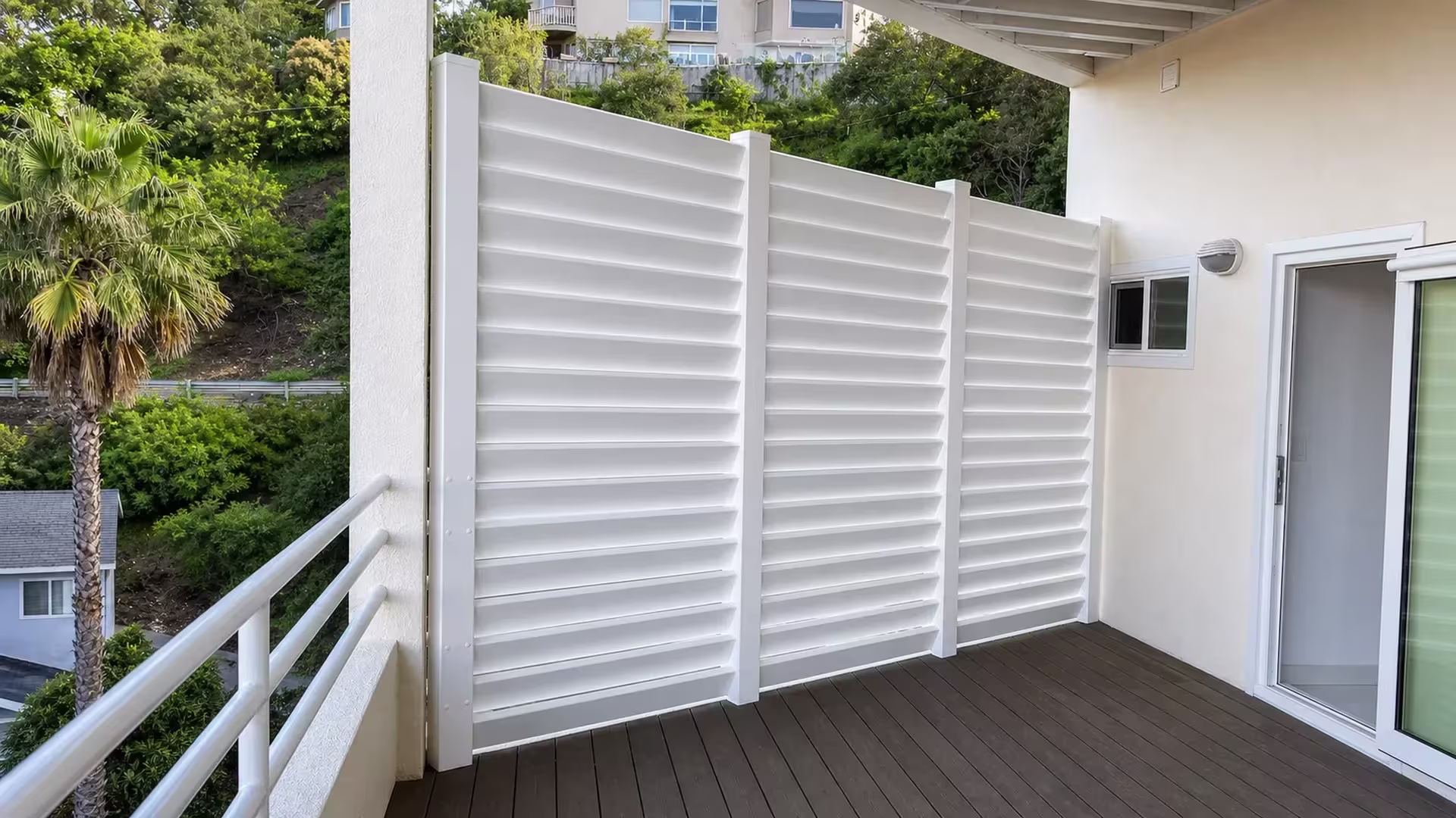 Elevated White vinyl picket fence lines a deck overlooking hillside homes in the distance