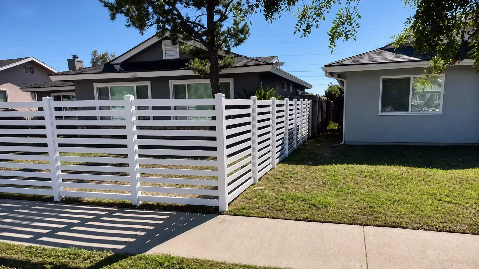 A square corner post turns this White vinyl picket fence off the sidewalk toward the rear yard