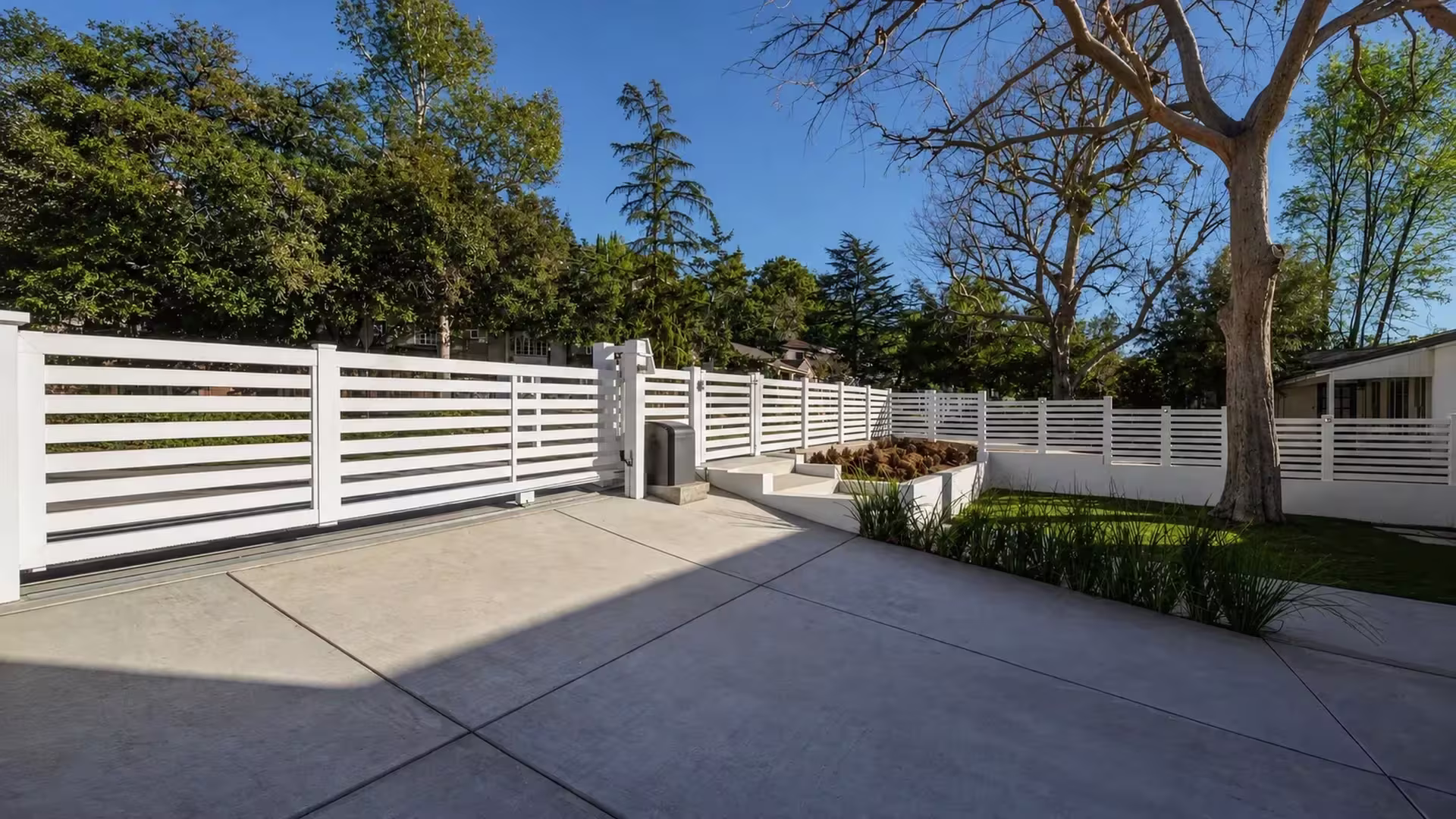 A White vinyl picket fence pairs a sliding driveway gate with a separate pedestrian gate near the steps