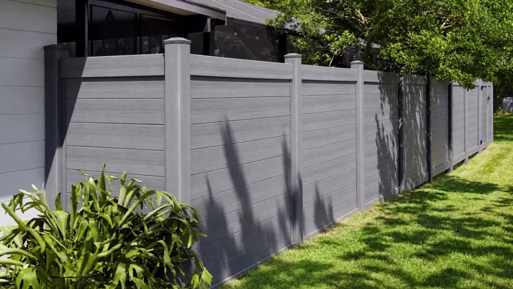 Arctic Blend vinyl horizontal privacy fence standing beside a light gray house with a screened porch