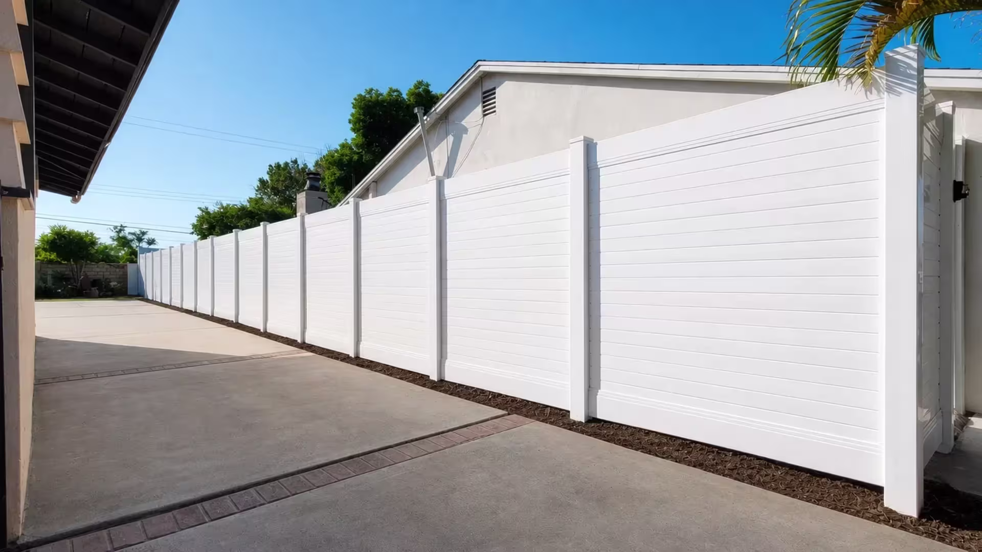 A masonry column anchors the return of a White vinyl horizontal privacy fence beside the house