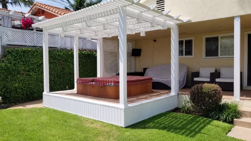 Wall-mounted television and a hot tub sit beneath the open lattice roof of a White vinyl pergola