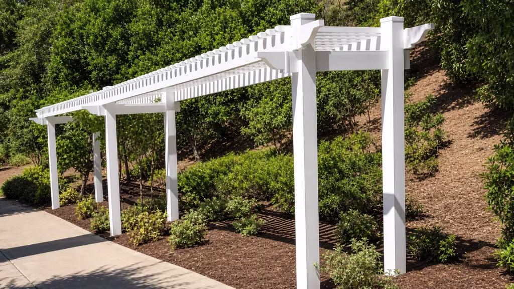 Six tall support posts carry a White vinyl pergola down the length of a sloped hillside yard