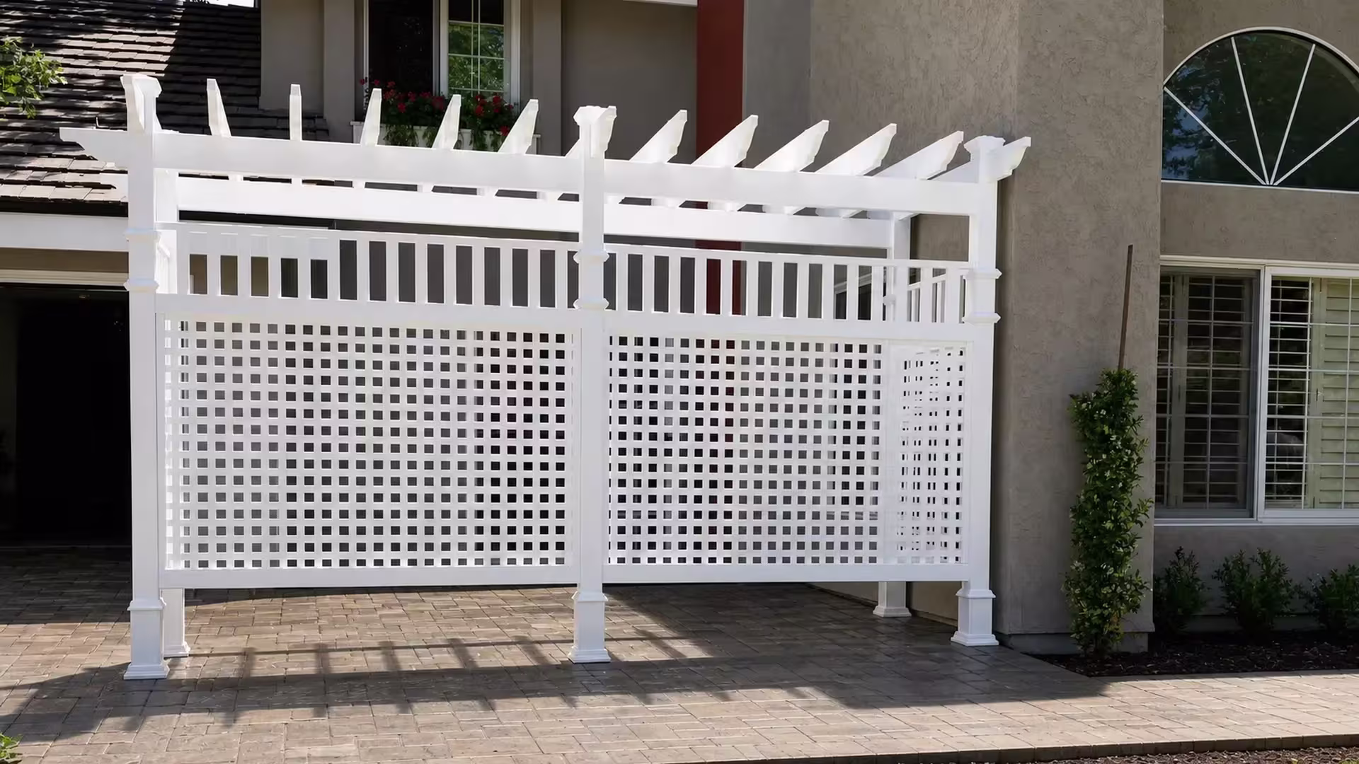 A lattice side screen on a White vinyl pergola runs along the house facade and its planting beds