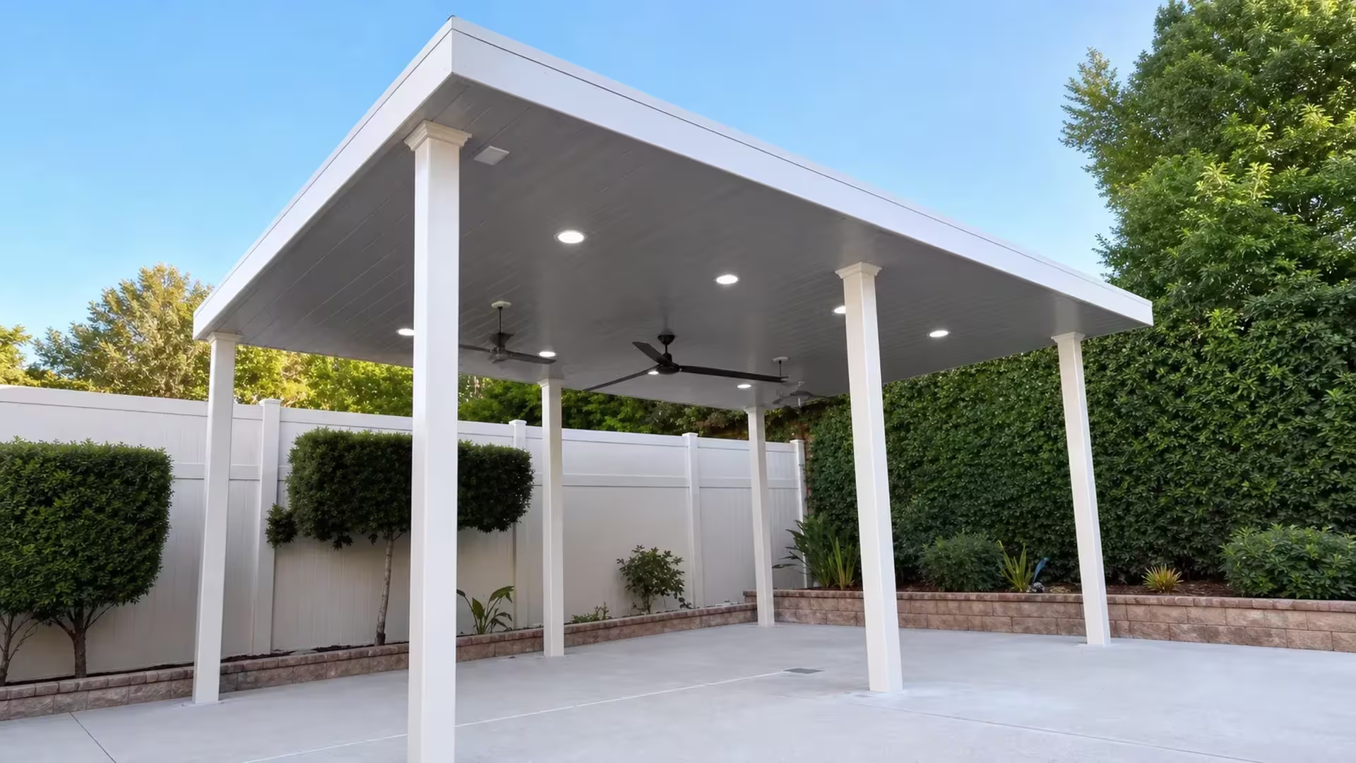 A brick border edges the concrete patio beneath a White vinyl pergola with a dark gray paneled underside