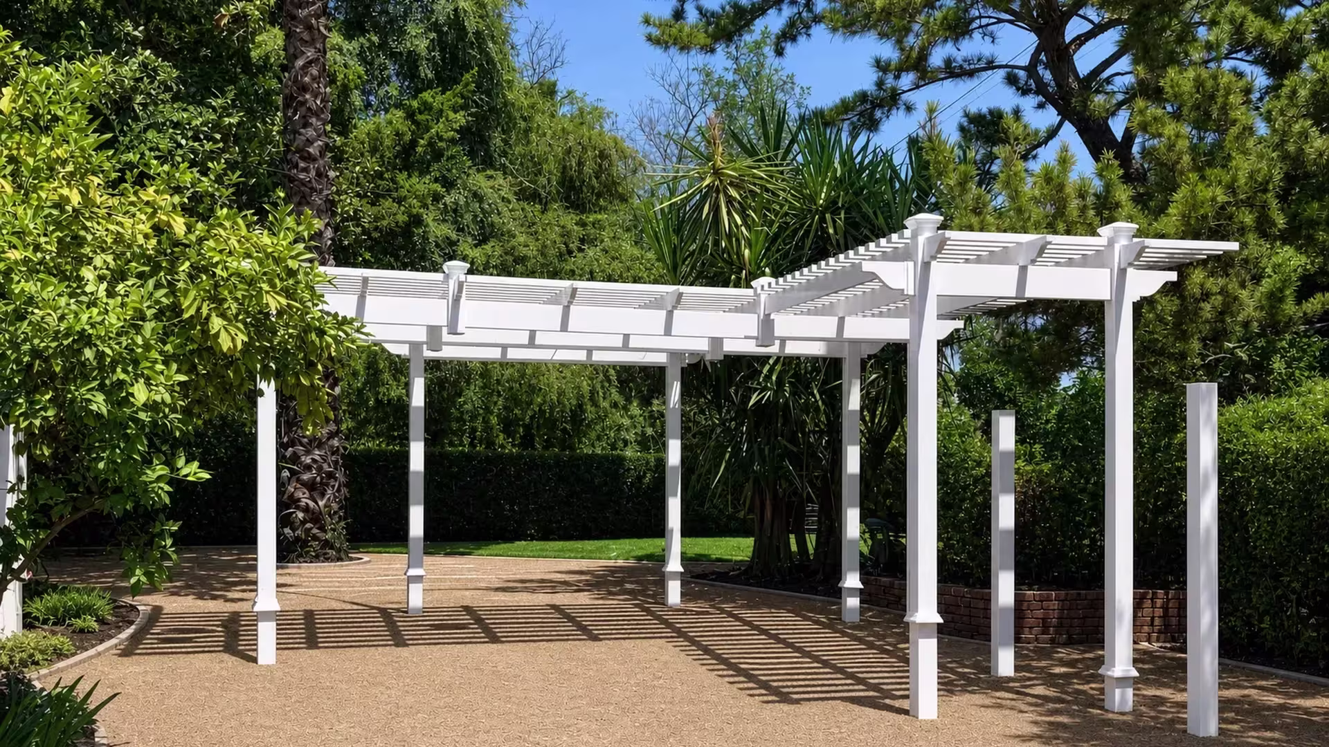 Two roof runs meet in an L-shaped layout where a White vinyl pergola extends above a brick retaining wall