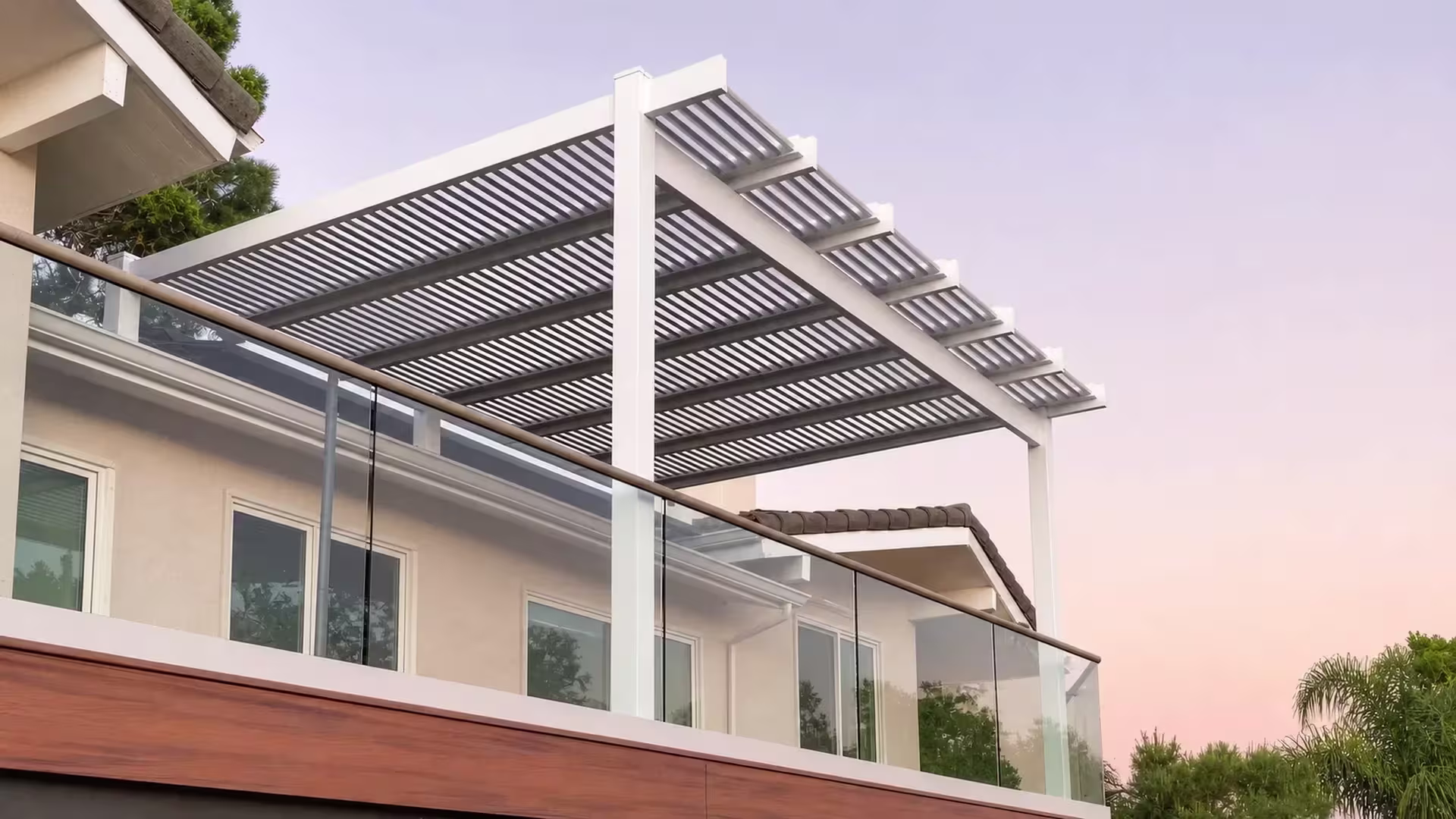 White vinyl picket patio cover shading a raised deck with a diagonal glass-panel railing