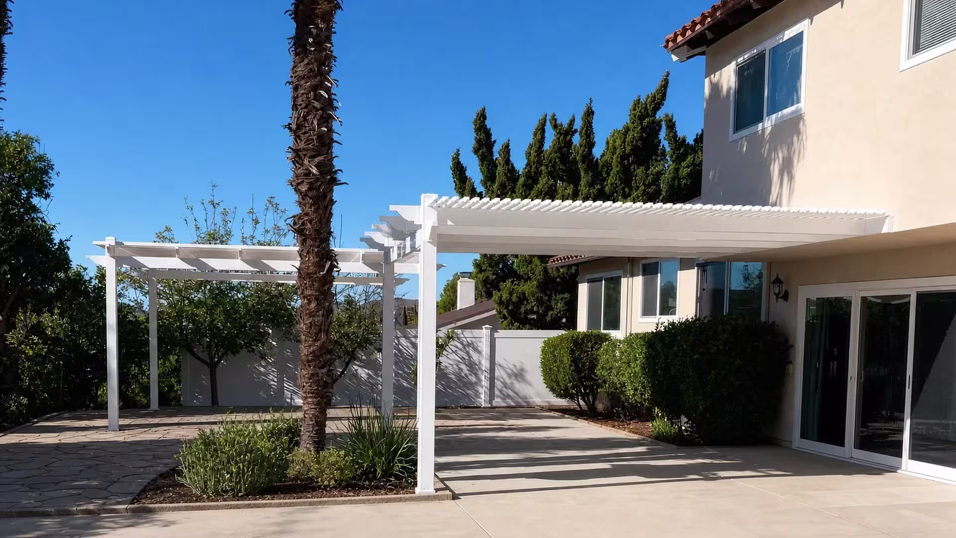 Two roof sections of a White vinyl picket patio cover converge at a tall center support post