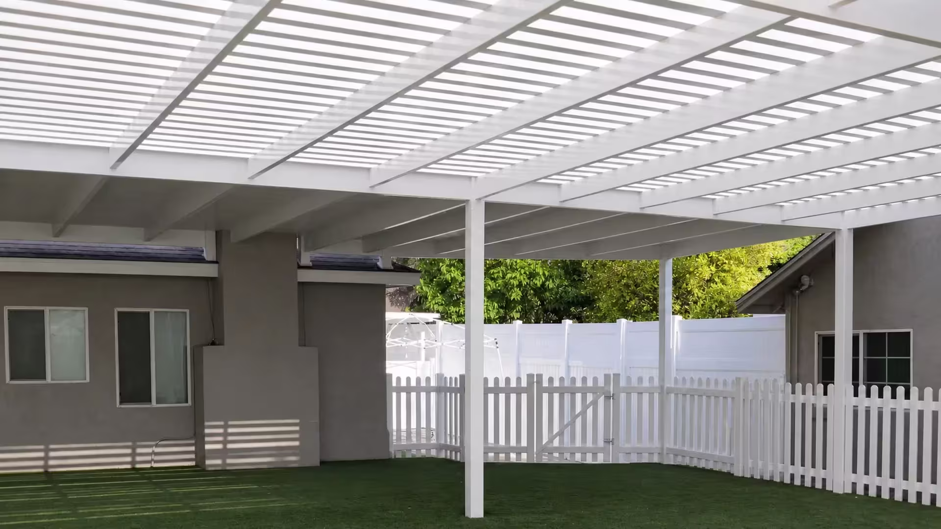 White vinyl picket patio cover filled with dense, evenly spaced overhead shade slats