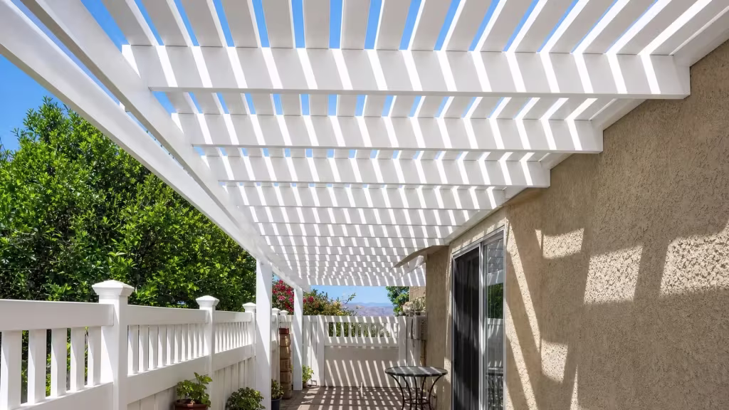 A sliding glass door and stucco overhang open onto this White vinyl picket patio cover