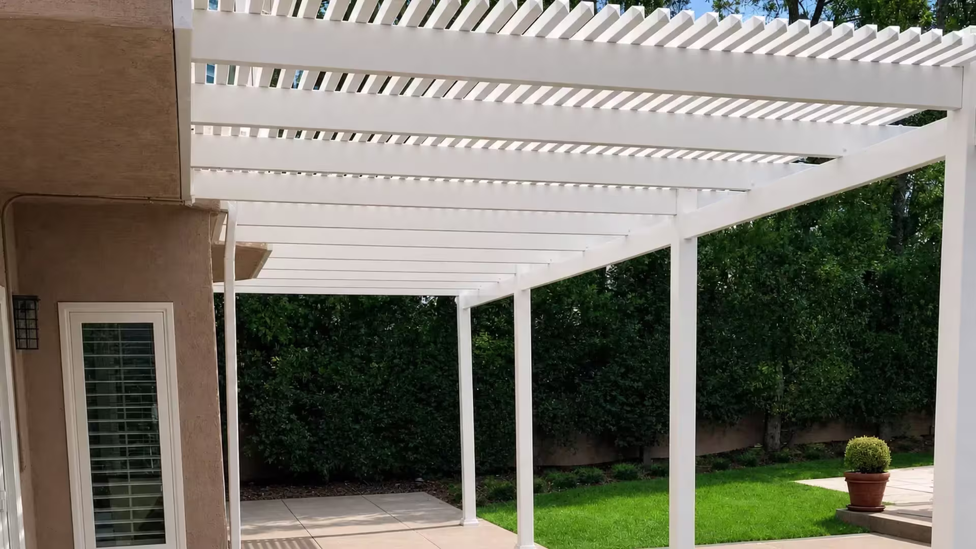 White vinyl picket patio cover forming an open lattice roof attached directly to the house
