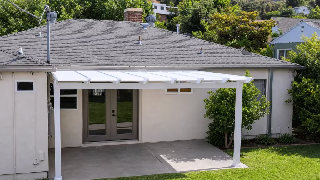 Gray stucco house with hillside homes beyond a White vinyl solid-roof picket patio cover