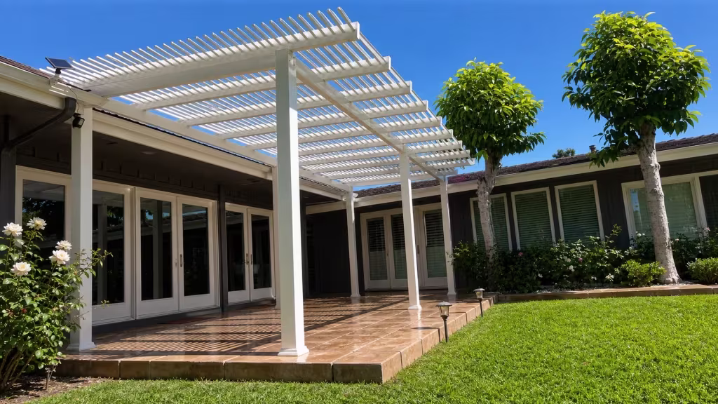 Raised paver border edges a tiled patio beneath a White vinyl open-slat picket patio cover