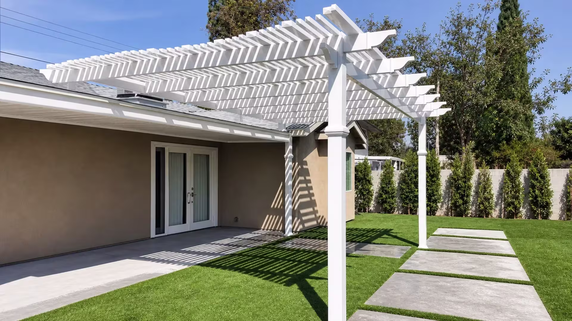 Gray metal tension rods brace the rafters of this White vinyl lattice-roof patio cover near a boundary wall