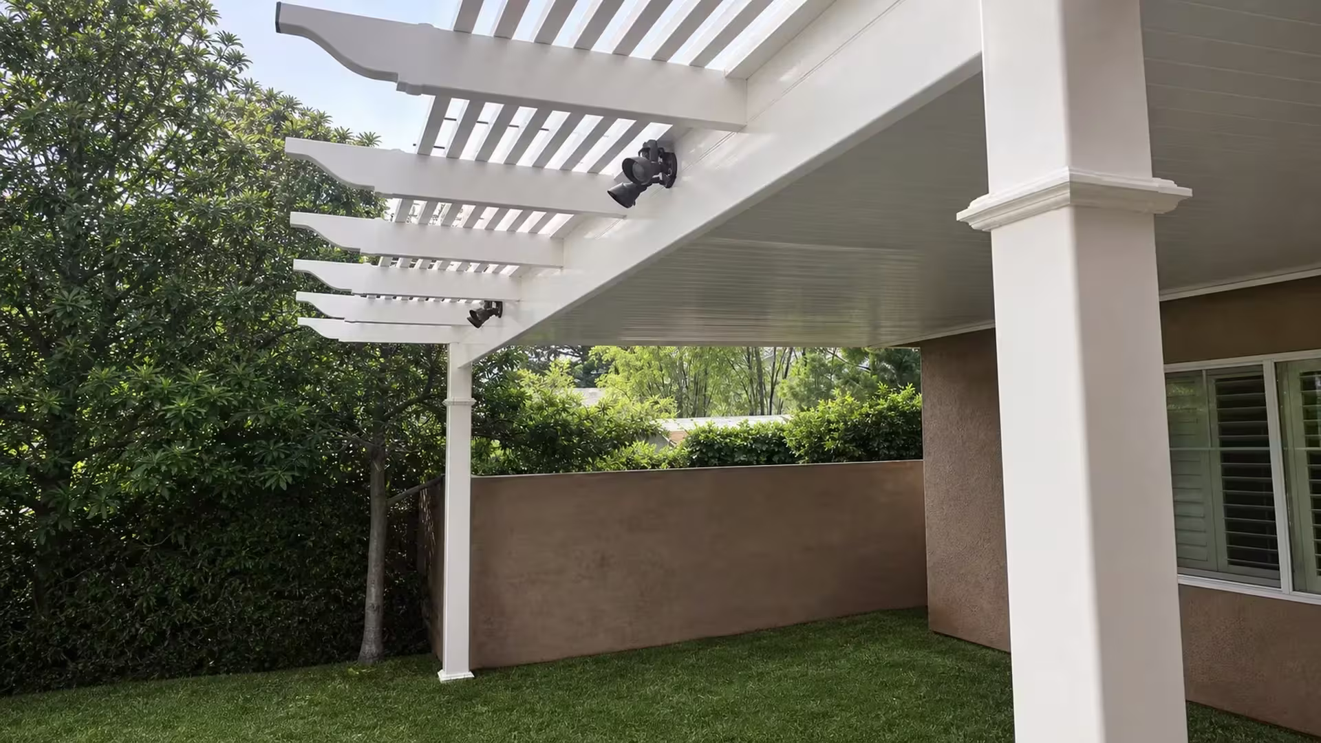 Solid roof panels join open lattice rafters in this White vinyl combination patio cover by a tan boundary wall