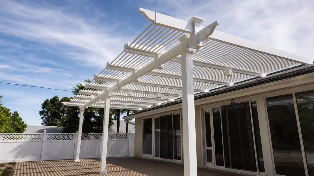 Rear lattice-topped fence stands near this White vinyl attached picket patio cover beside sliding glass doors
