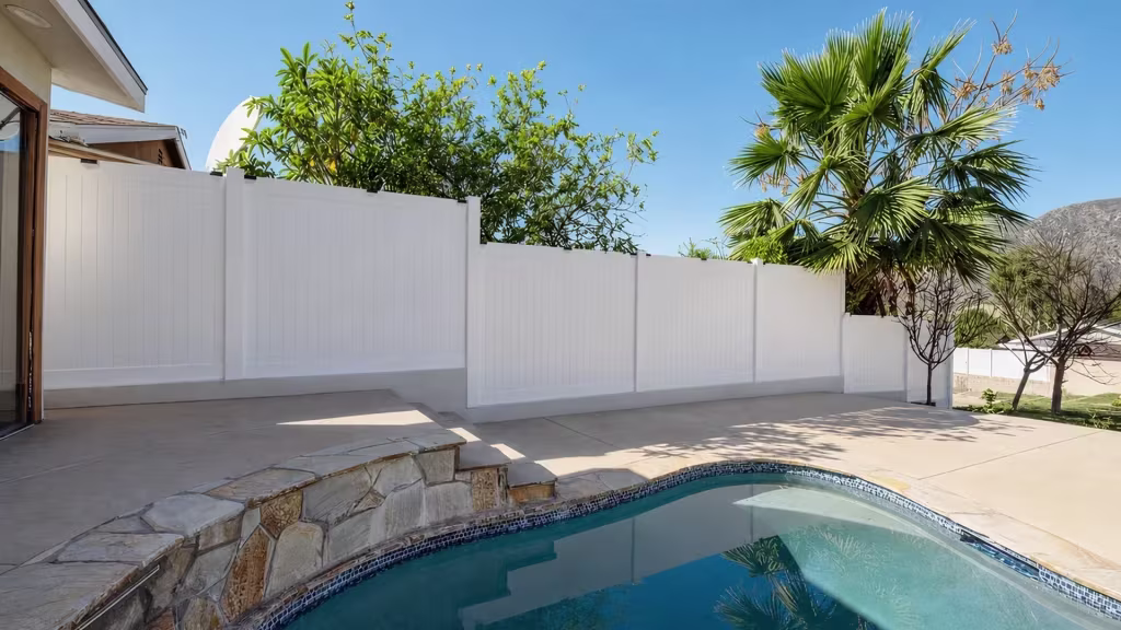 White vinyl privacy pool fence with panels stepping down the yard toward a distant mountain backdrop