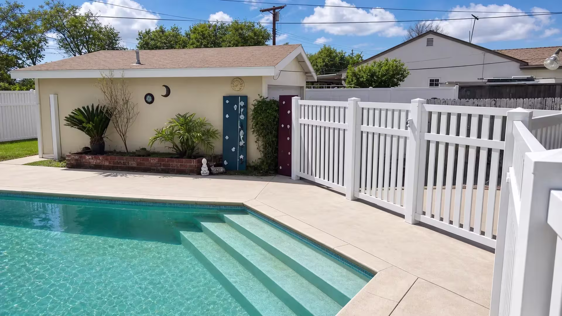 Cream vinyl pool safety fence with evenly spaced pickets set back from three broad submerged entry steps