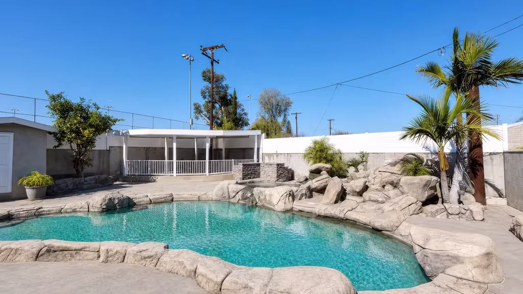 Along the edge of a raised rear patio, a White vinyl pool fence forms adjoining rectangular railing sections