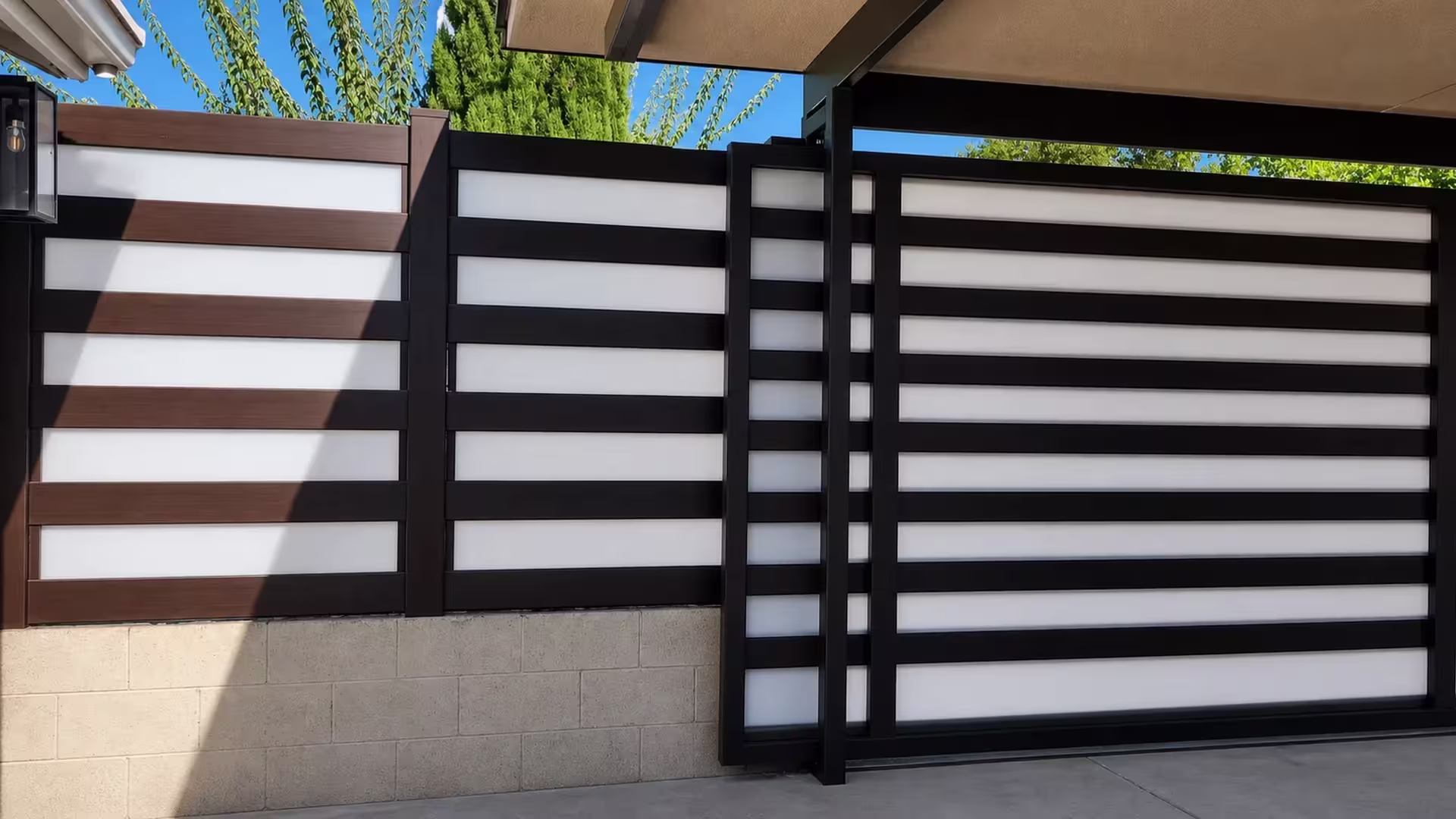 Carport roofline shelters this Dark Walnut vinyl privacy fence with alternating acrylic bands
