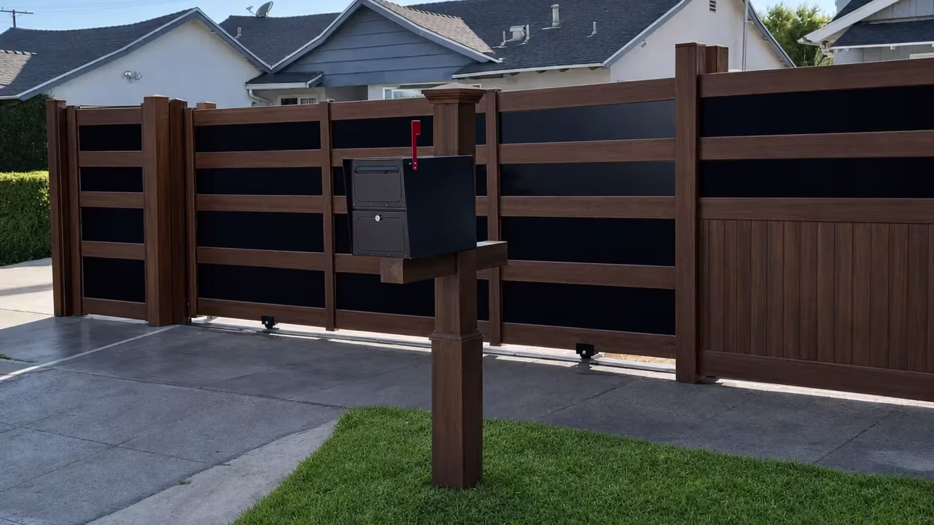Rolling driveway gate adjoins this Dark Walnut vinyl fence with acrylic panels near the mailbox post