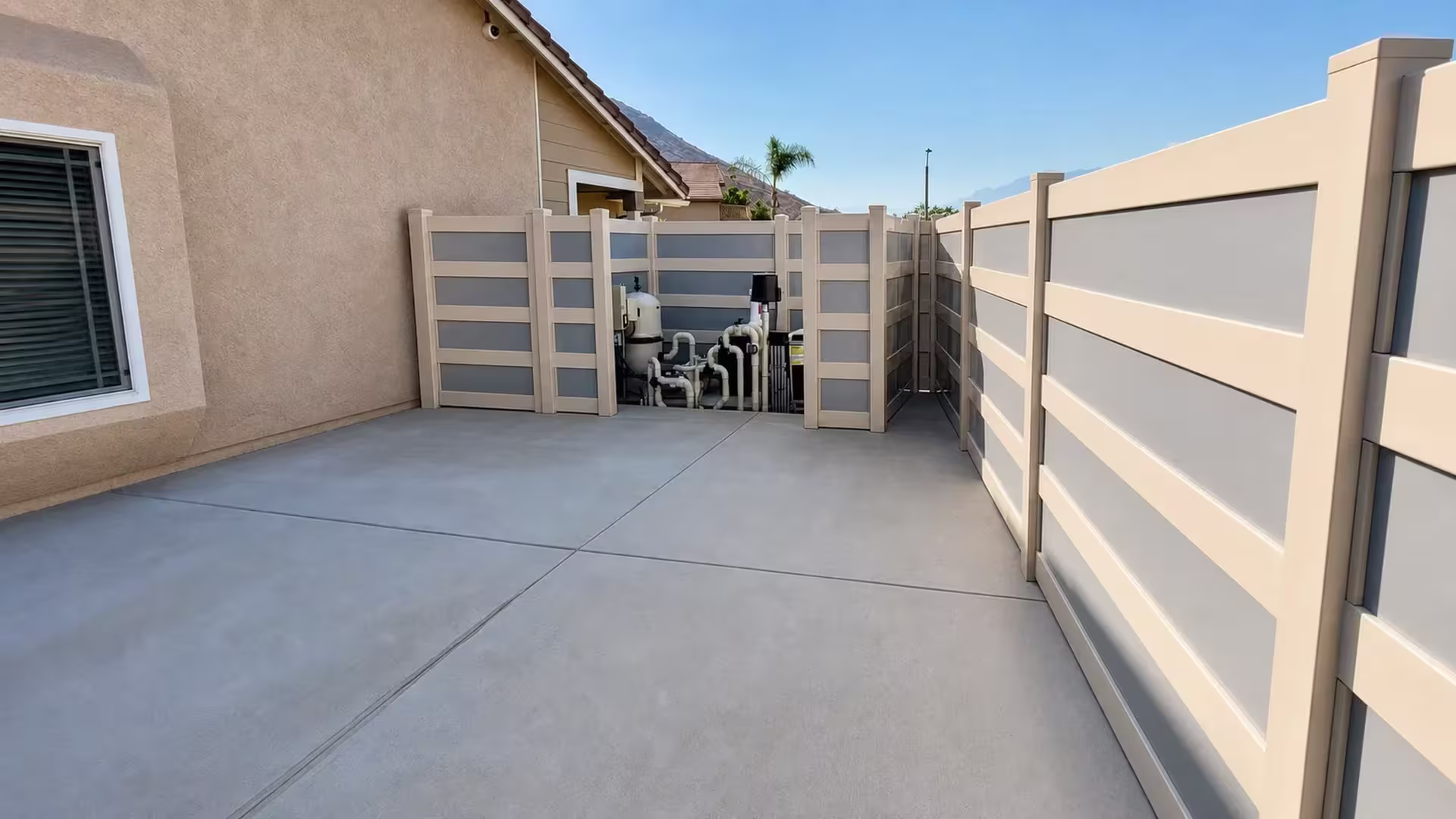 Pool equipment sits behind this Tan vinyl privacy fence with acrylic along a concrete side yard