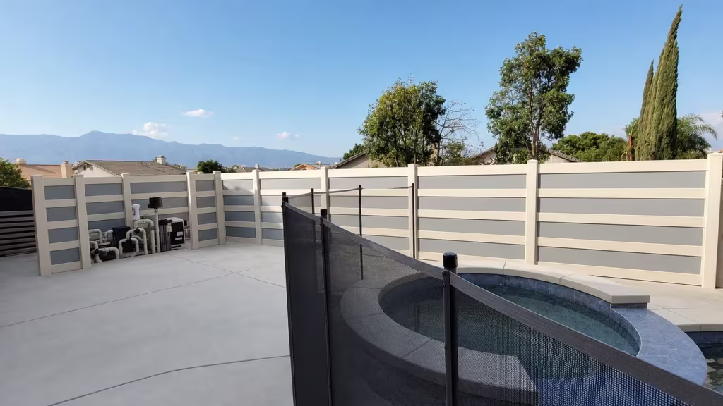 A raised circular spa borders this Tan vinyl privacy fence with acrylic wrapping the backyard pool