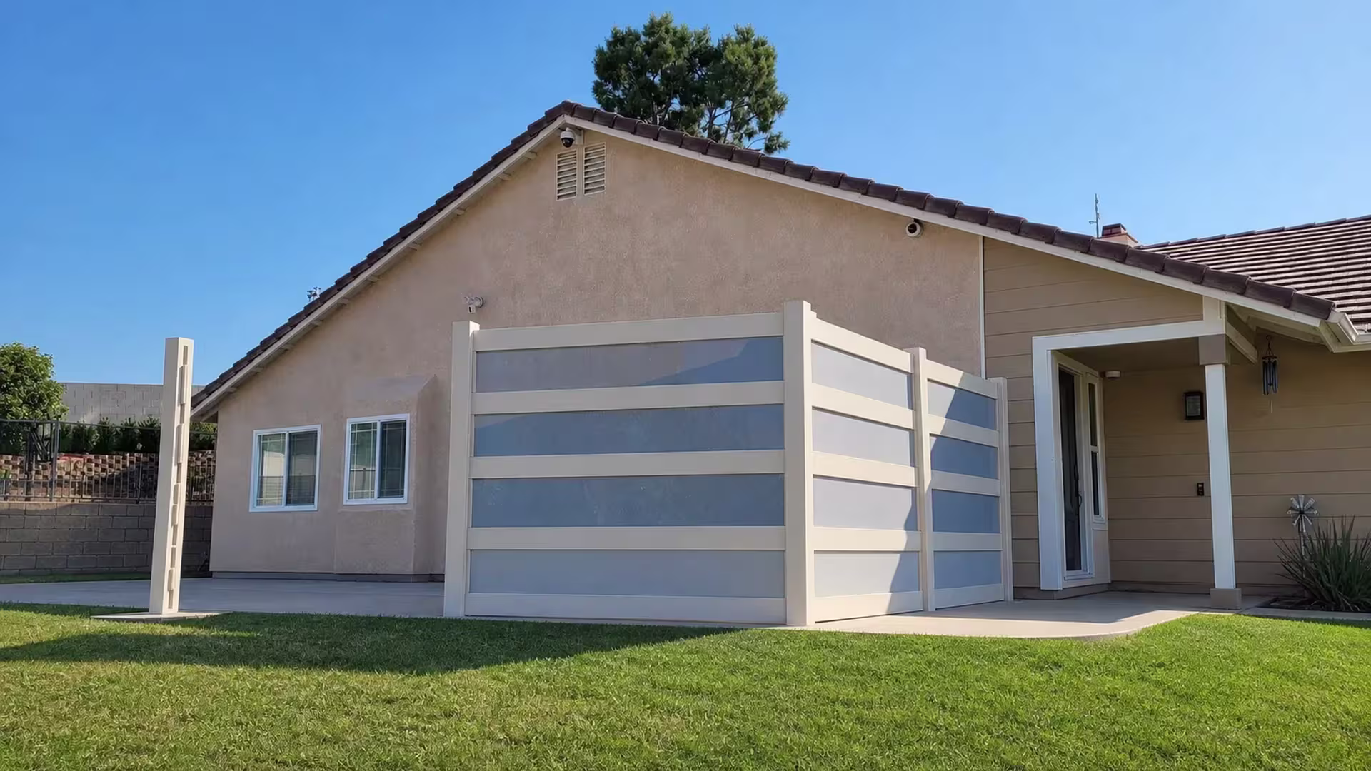 Front porch marks the end of this Tan vinyl privacy fence with blue gray acrylic bands