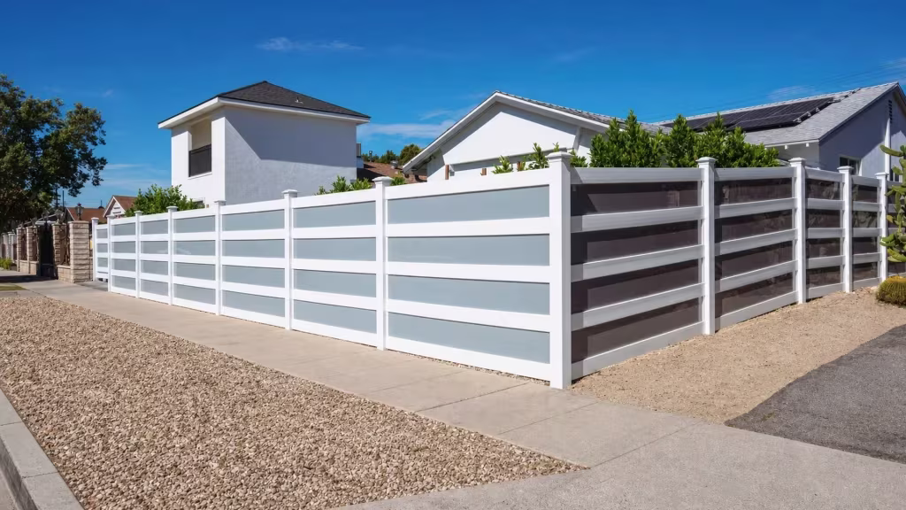 Pyramidal post caps top every post of this White vinyl privacy fence with acrylic at its corner return