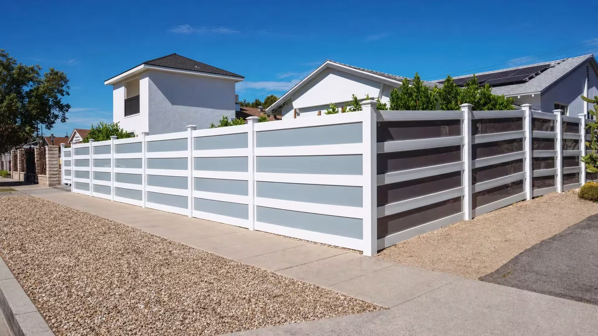 Pyramidal post caps top every post of this White vinyl privacy fence with acrylic at its corner return