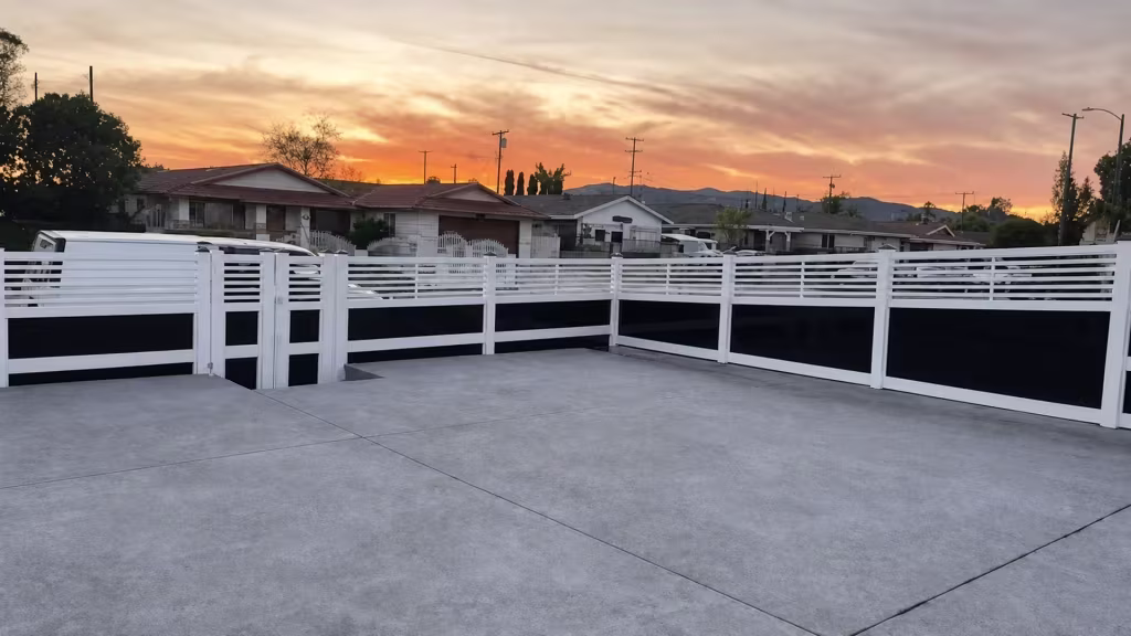 Distant hills rise beyond this White vinyl privacy fence with acrylic enclosing a broad concrete yard