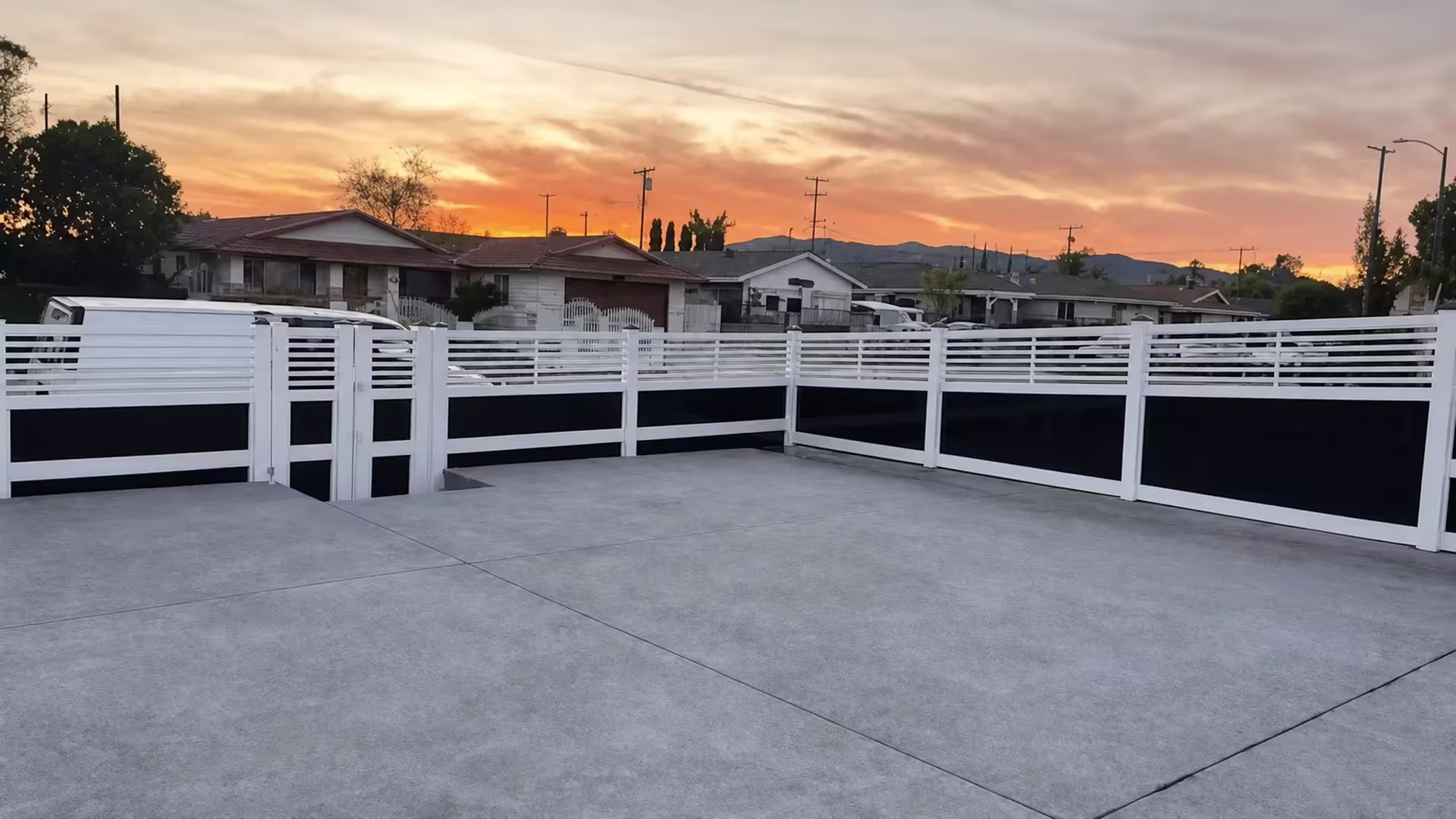 Distant hills rise beyond this White vinyl privacy fence with acrylic enclosing a broad concrete yard