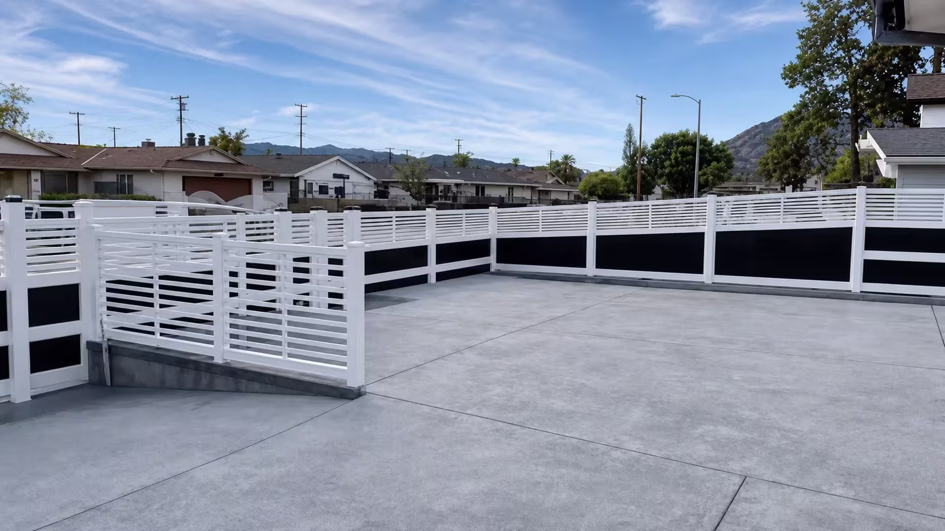 An L-shaped rooftop patio is wrapped by this White vinyl privacy fence, its acrylic infill topped with horizontal slats